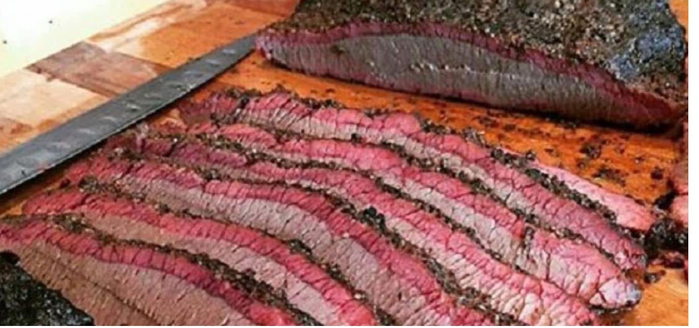 Beef brisket sliced on a cutting board showing pink smoke ring